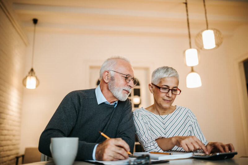 Senior couple filling out paperwork, wearing glasses