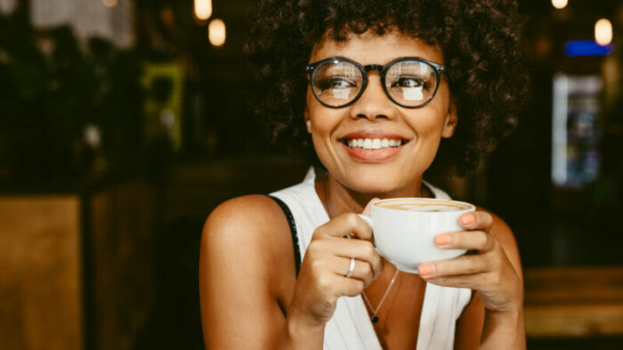 Beautiful young woman wearing glasses and drinking coffee.