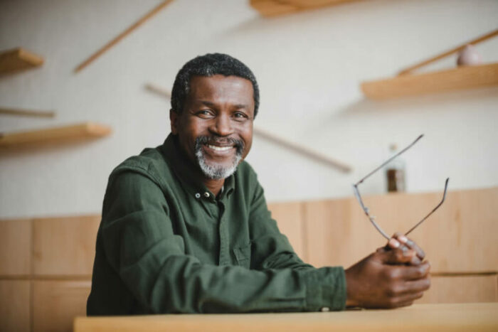 Middle-aged man holding glasses in from of wood shelf display