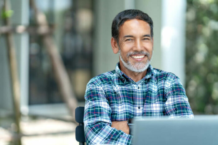 Middle-aged man in front of laptop, smiling