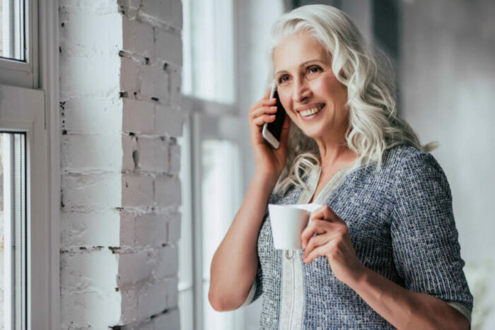 Senior woman on phone holding coffee cup