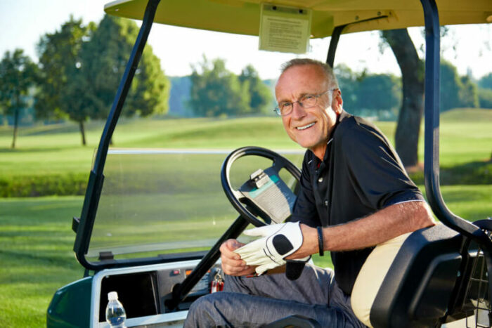 Senior man in golf cart smiling.