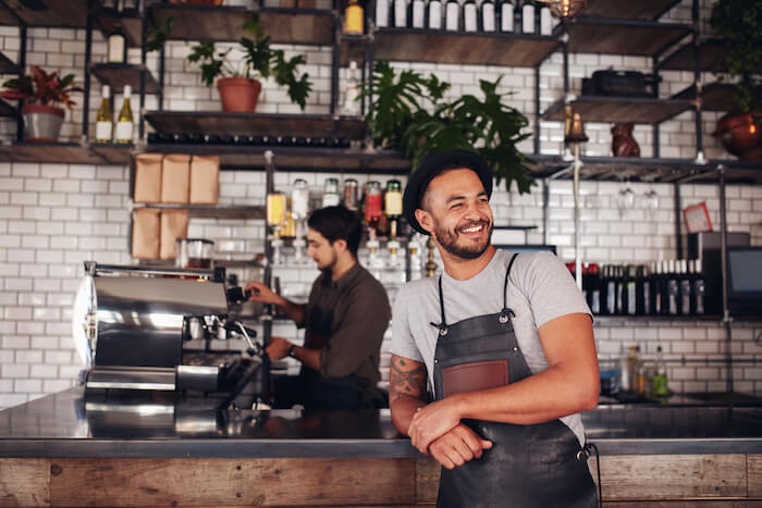 Cafe owner stands in front of counter.